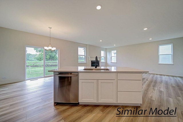 kitchen featuring dishwasher, white cabinets, sink, hanging light fixtures, and an island with sink