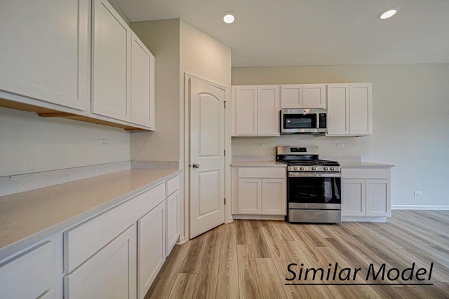 kitchen with white cabinets, stainless steel appliances, and light hardwood / wood-style floors