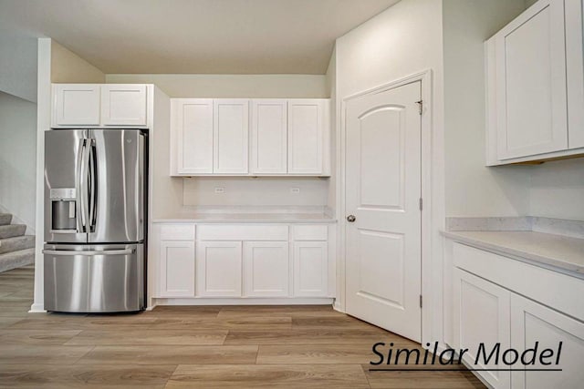 kitchen featuring white cabinets, light hardwood / wood-style floors, and stainless steel refrigerator with ice dispenser