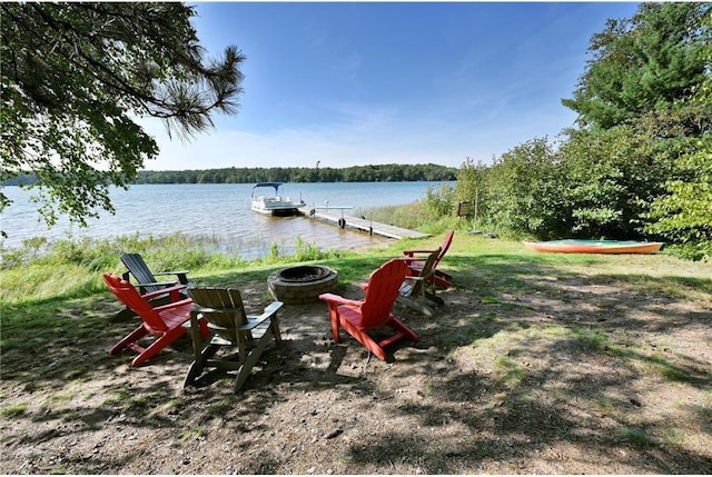 view of yard featuring a fire pit, a boat dock, and a water view