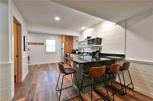 interior space featuring a breakfast bar area, stainless steel appliances, kitchen peninsula, and dark hardwood / wood-style flooring