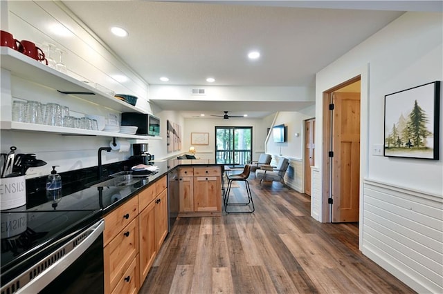 kitchen featuring ceiling fan, a kitchen bar, sink, dark hardwood / wood-style flooring, and stainless steel appliances