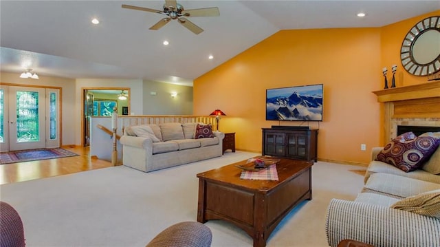 carpeted living room featuring lofted ceiling, ceiling fan, and a tiled fireplace