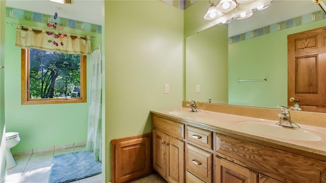 bathroom with tile floors, vanity with extensive cabinet space, toilet, and double sink