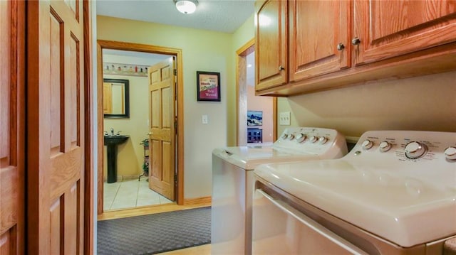 laundry area with cabinets, independent washer and dryer, and light tile floors