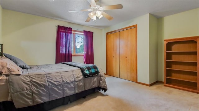 bedroom with light colored carpet, ceiling fan, and a closet