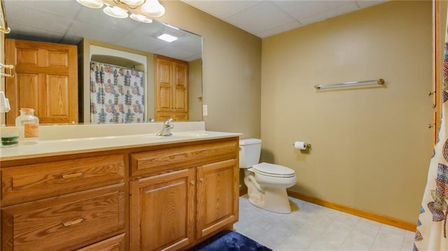 bathroom with vanity, toilet, tile floors, and a paneled ceiling