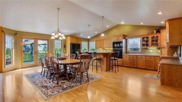 dining space with high vaulted ceiling, light hardwood / wood-style flooring, and a chandelier