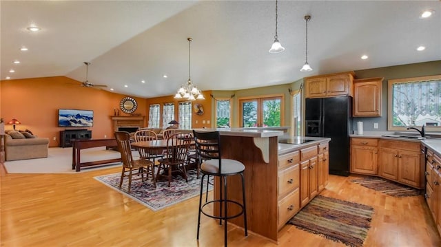 kitchen featuring a center island, light wood-type flooring, a breakfast bar area, decorative light fixtures, and black appliances