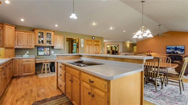 kitchen with ceiling fan with notable chandelier, light hardwood / wood-style flooring, hanging light fixtures, and a center island