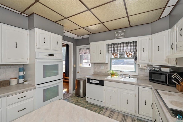 kitchen featuring sink, decorative backsplash, white cabinets, and white appliances