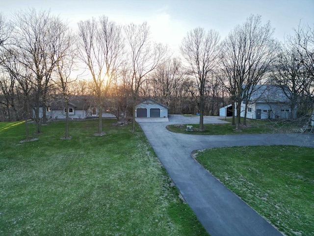 yard at dusk with a garage and an outdoor structure