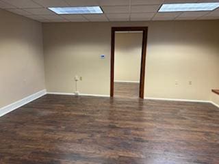 unfurnished room with dark hardwood / wood-style flooring and a paneled ceiling