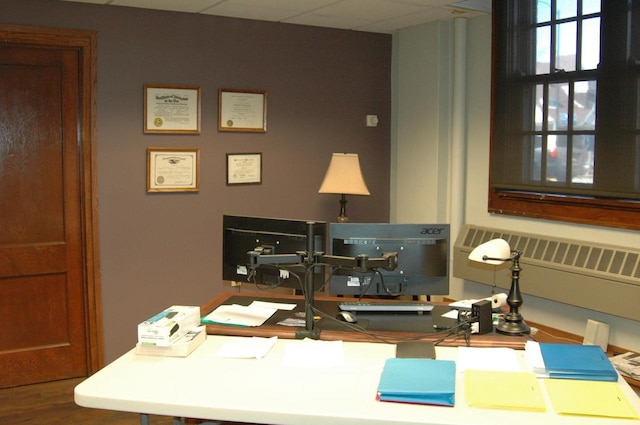 office area with a drop ceiling, hardwood / wood-style flooring, and radiator