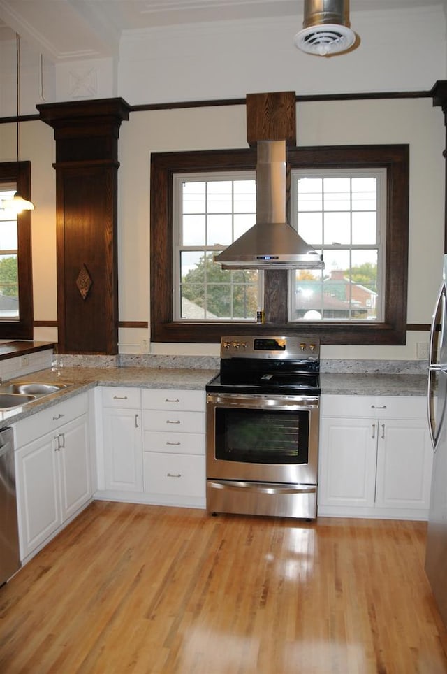 kitchen with appliances with stainless steel finishes, white cabinets, island exhaust hood, light hardwood / wood-style flooring, and light stone countertops