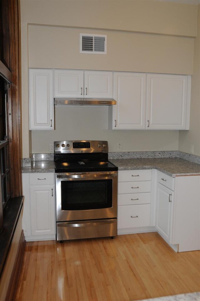 kitchen featuring white cabinets, stainless steel electric range oven, light wood-type flooring, and light stone countertops