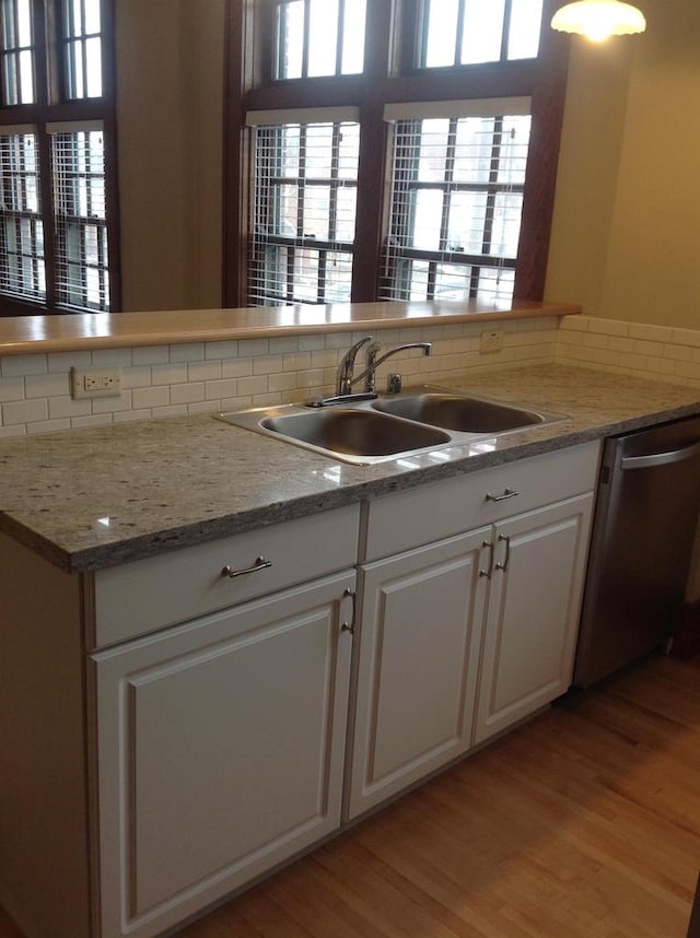 kitchen featuring light hardwood / wood-style floors, dishwasher, tasteful backsplash, white cabinets, and sink