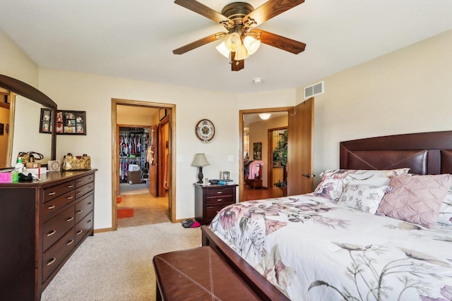 bedroom with light colored carpet, a spacious closet, ceiling fan, and a closet