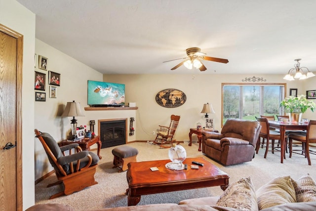 carpeted living room featuring ceiling fan with notable chandelier