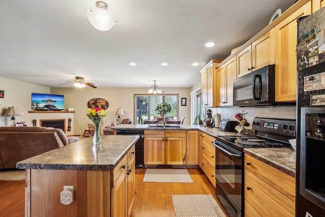 kitchen with sink, light hardwood / wood-style floors, tasteful backsplash, ceiling fan with notable chandelier, and black appliances