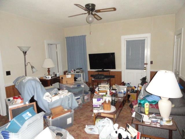 living room with ceiling fan and wood walls