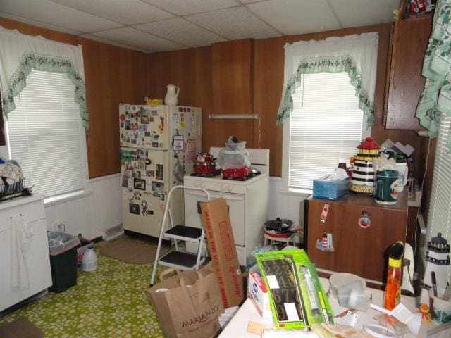 kitchen featuring washer / clothes dryer, white fridge, and wood walls