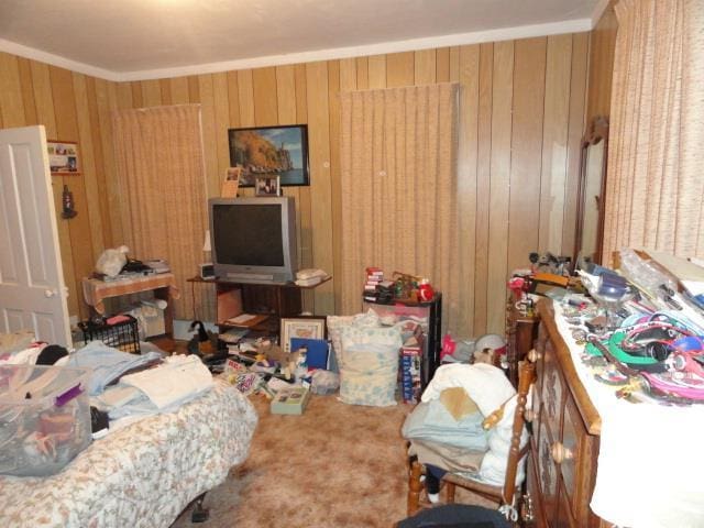 bedroom with crown molding, carpet, and wood walls