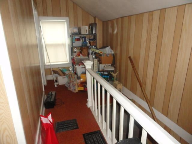 interior space with lofted ceiling, wooden walls, and carpet