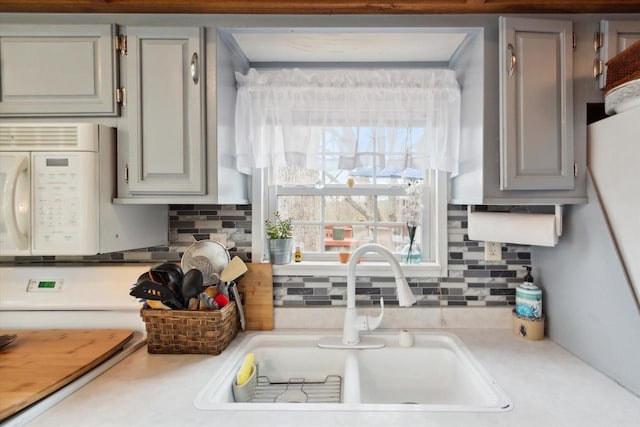 kitchen featuring sink, tasteful backsplash, and gray cabinetry