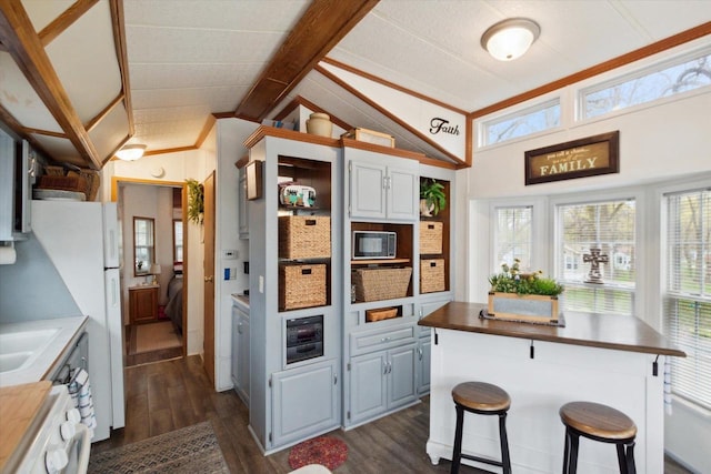 kitchen with a kitchen bar, lofted ceiling with beams, white cabinetry, wooden counters, and dark hardwood / wood-style flooring