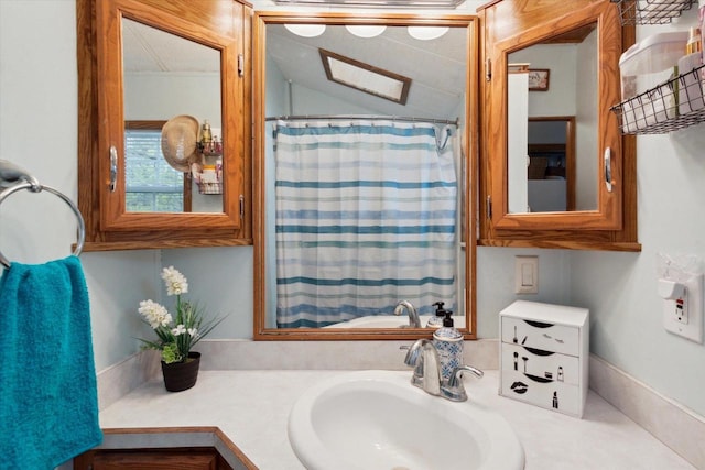 bathroom featuring lofted ceiling with skylight and sink