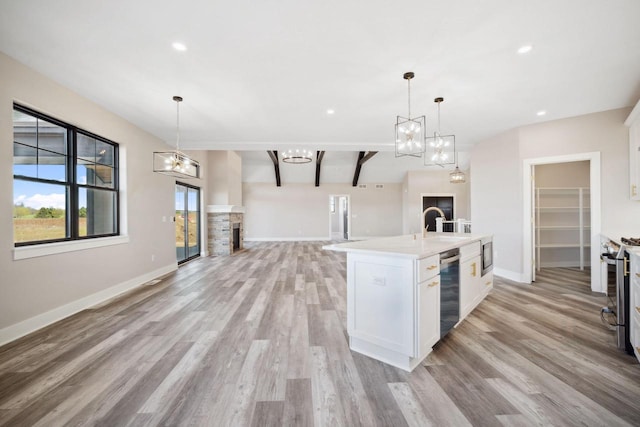 kitchen with light hardwood / wood-style flooring, beam ceiling, white cabinets, and decorative light fixtures