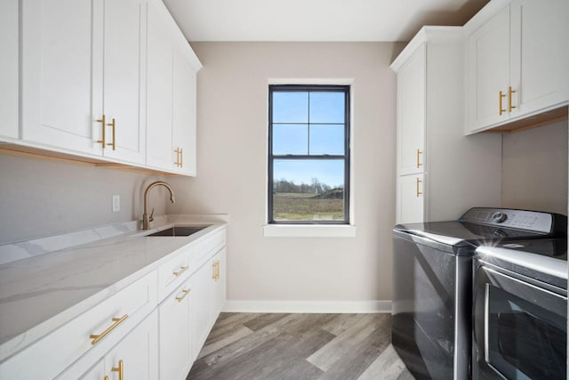 laundry area with cabinets, sink, washing machine and dryer, and hardwood / wood-style flooring