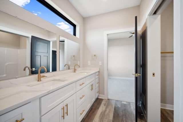 bathroom with wood-type flooring, ceiling fan, large vanity, and double sink