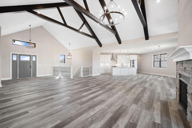 unfurnished living room with beamed ceiling, a fireplace, high vaulted ceiling, sink, and hardwood / wood-style floors