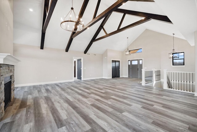 unfurnished living room featuring high vaulted ceiling, hardwood / wood-style floors, beam ceiling, and a stone fireplace