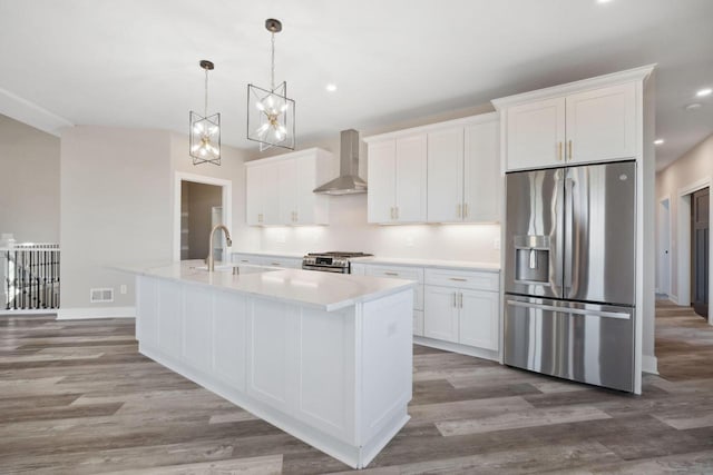 kitchen featuring wall chimney exhaust hood, appliances with stainless steel finishes, and hardwood / wood-style flooring