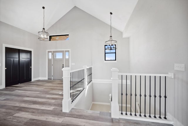 foyer entrance featuring a chandelier, wood-type flooring, and high vaulted ceiling