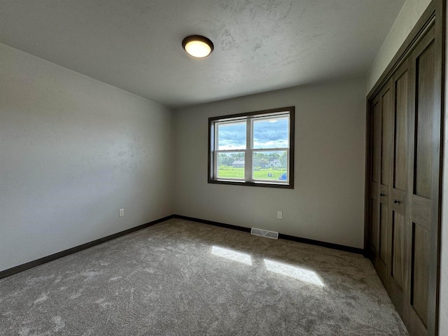 unfurnished bedroom with light colored carpet, a closet, and a textured ceiling