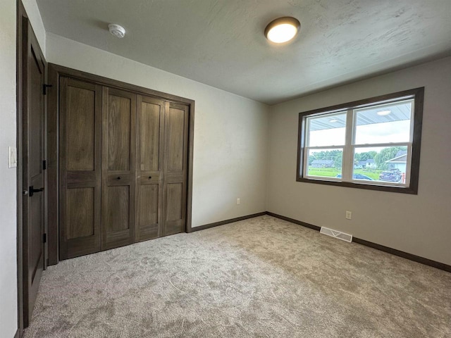 unfurnished bedroom featuring light colored carpet and a closet