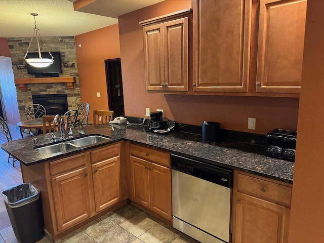 kitchen with kitchen peninsula, dark stone countertops, a fireplace, sink, and stainless steel dishwasher