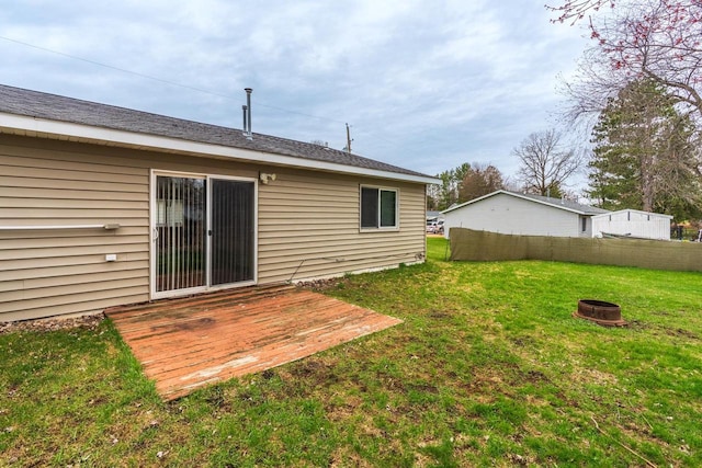 rear view of house featuring a deck, a fire pit, and a lawn