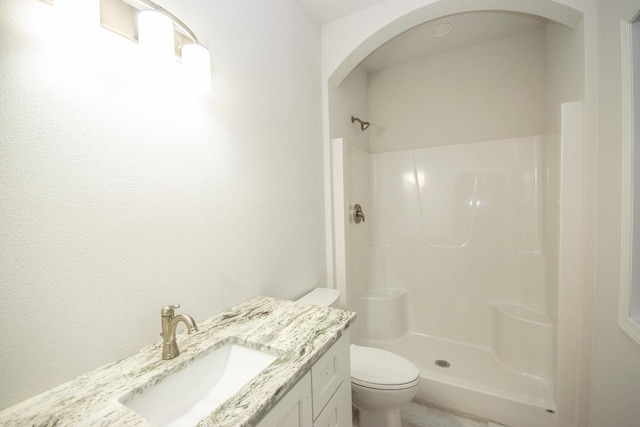 bathroom featuring a shower, vanity, and toilet