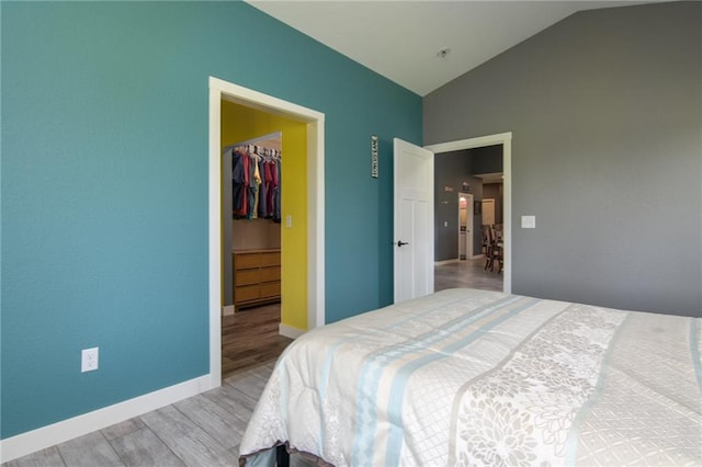 bedroom with a closet, vaulted ceiling, a walk in closet, and wood-type flooring