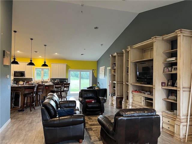 living room with vaulted ceiling, sink, and light wood-type flooring