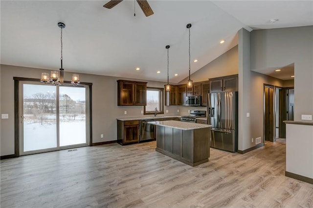 kitchen with appliances with stainless steel finishes, decorative light fixtures, a center island, light hardwood / wood-style floors, and dark brown cabinets