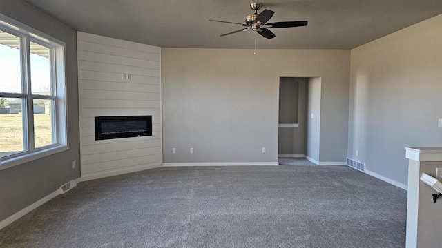 unfurnished living room featuring carpet flooring, ceiling fan, and a large fireplace