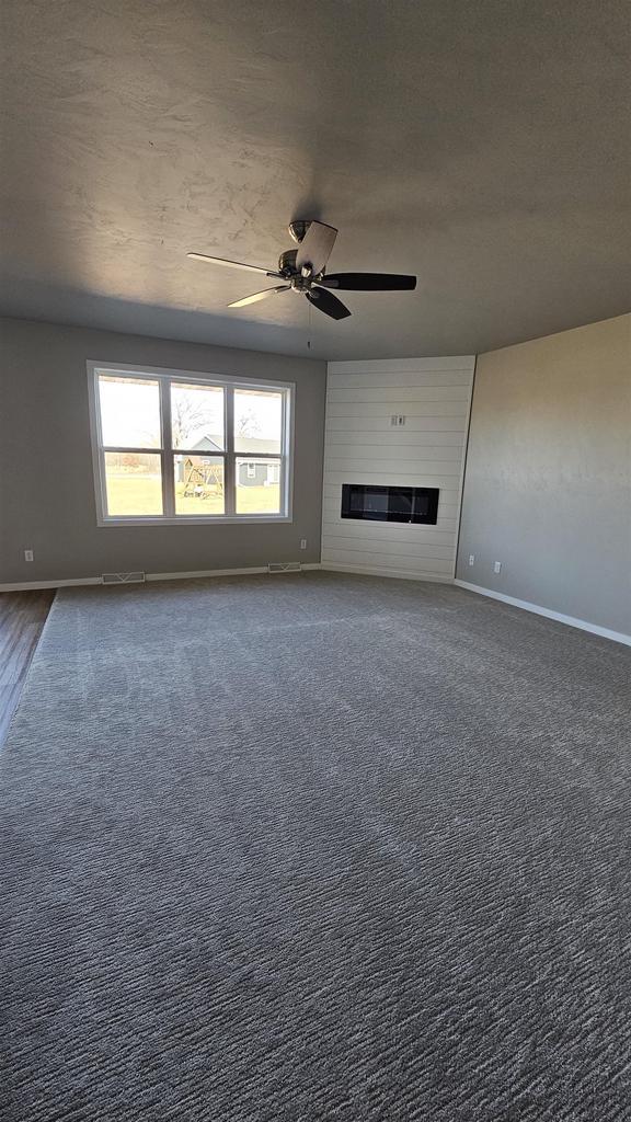 unfurnished living room featuring a wealth of natural light, a fireplace, and ceiling fan