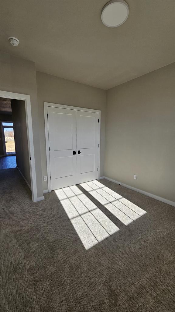 unfurnished bedroom with dark carpet and a closet