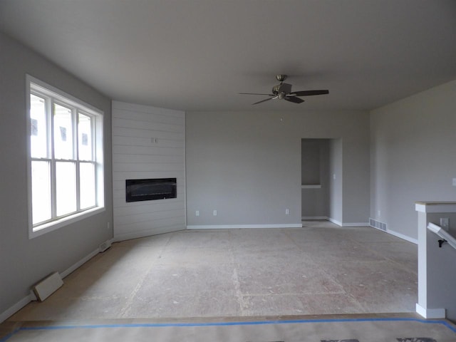 unfurnished living room with ceiling fan and a large fireplace